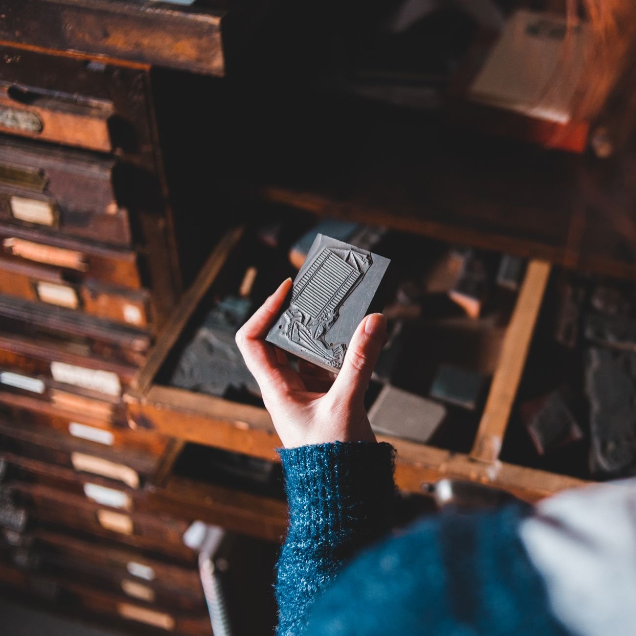 Typography worker near cabinet with professional printing tools and letterpress equipment.